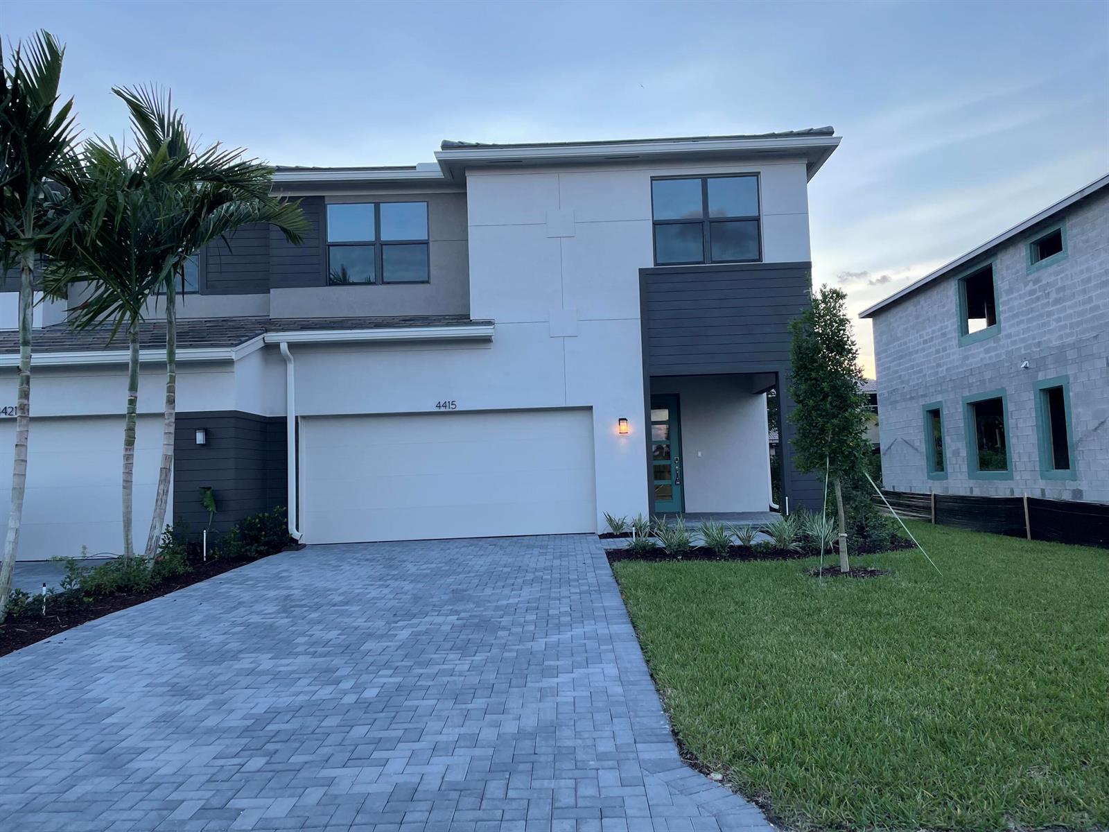 A two-story modern townhouse with a paved driveway, white stucco, and dark horizontal siding — 4415 Arcturus Lane, Lake Worth FL 33467, LAKE WORTH, FL