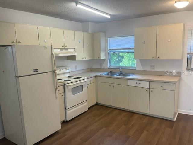 A kitchen features white cabinets, a white refrigerator, a white stove, and wood-look flooring — 3800 18TH AVENUE S UNIT 4, ST PETERSBURG, FL