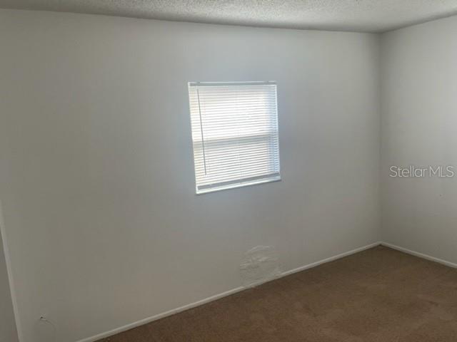 An empty bedroom features white walls, beige carpet, and a single window with closed blinds — 3800 18TH AVENUE S UNIT 4, ST PETERSBURG, FL