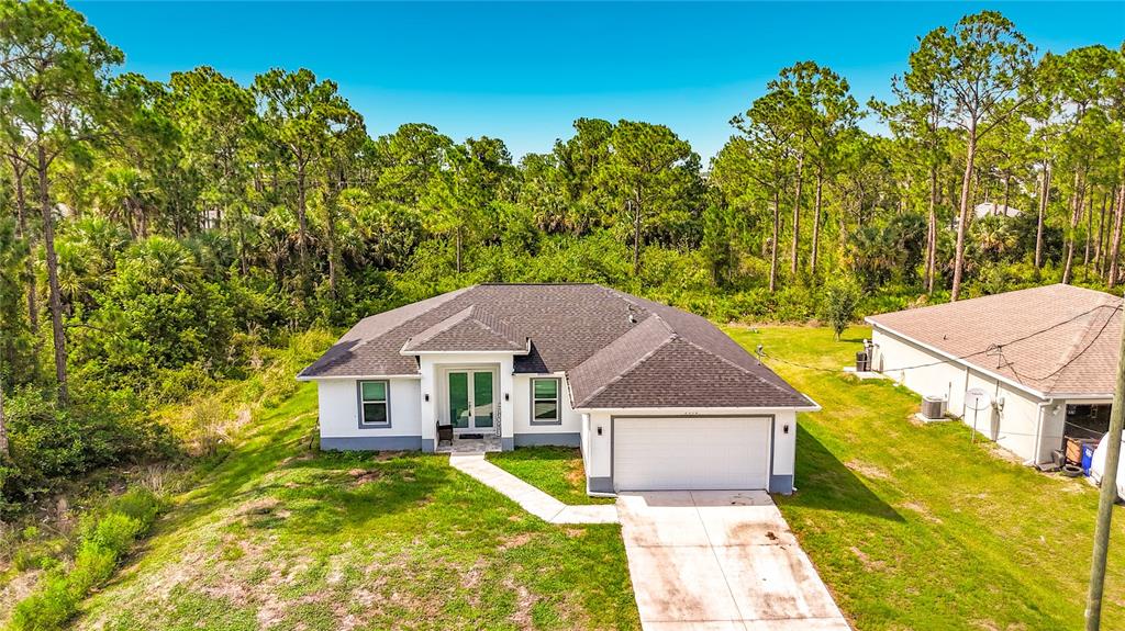An aerial view shows a single-story white house with a dark roof and attached garage — 3312 72ND STREET W, LEHIGH ACRES, FL