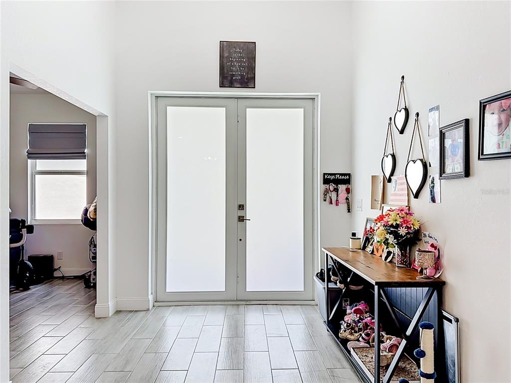 An entryway features double frosted glass doors, wood-look tile flooring, and a console table — 3312 72ND STREET W, LEHIGH ACRES, FL