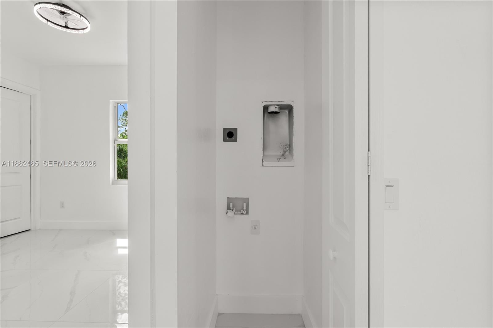 This laundry closet features plumbing hookups, a recessed dryer vent, and white tile flooring — 936 Anthony E, Lehigh Acres FL 33974, LEHIGH ACRES, FL