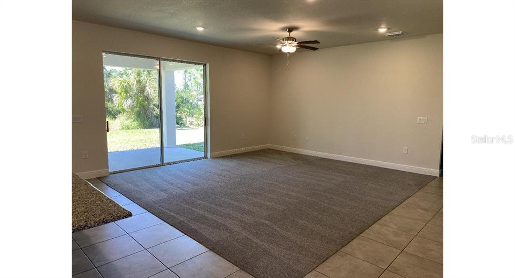 A living room features beige carpeting, a ceiling fan, and sliding glass doors to a patio — 4501 CARRIZAL TERRACE, NORTH PORT, FL