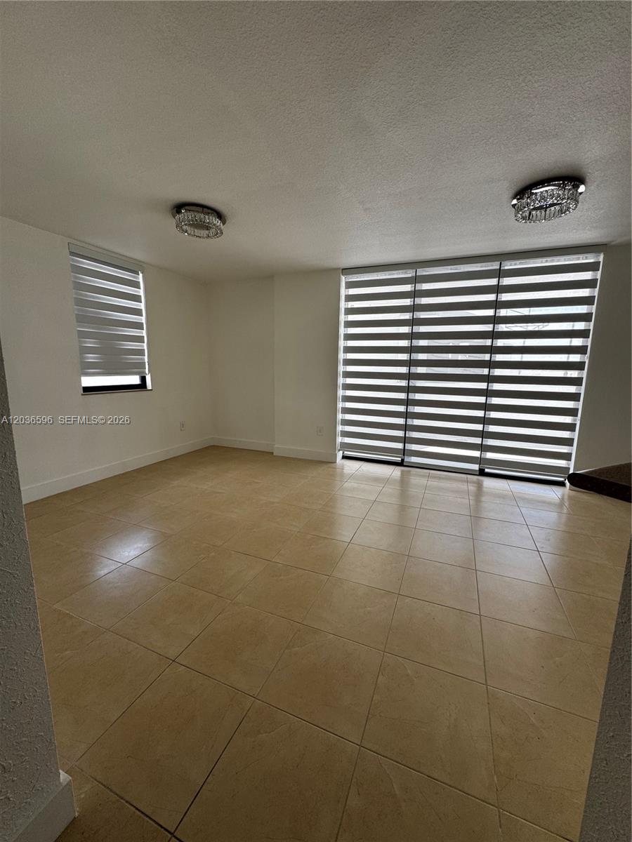 An empty room features beige tile flooring, white walls, and two windows with striped shades — 2301 SW 27th Ave # 503, Miami FL 33145, MIAMI, FL