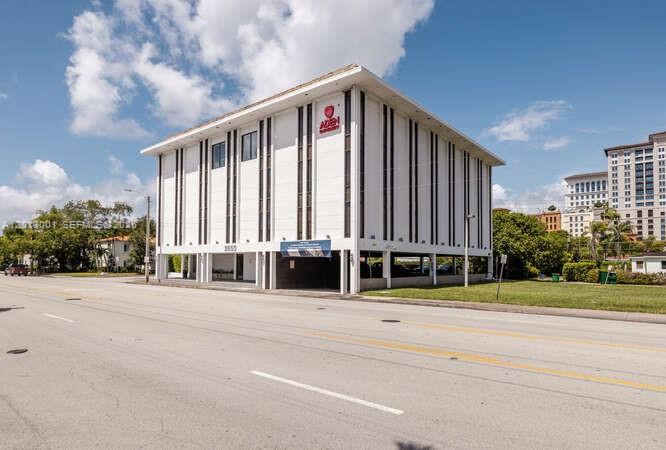 A three-story white commercial building with vertical dark accents stands beside a paved road — 2850 S Douglas Rd, Coral Gables FL 33134, CORAL GABLES, FL