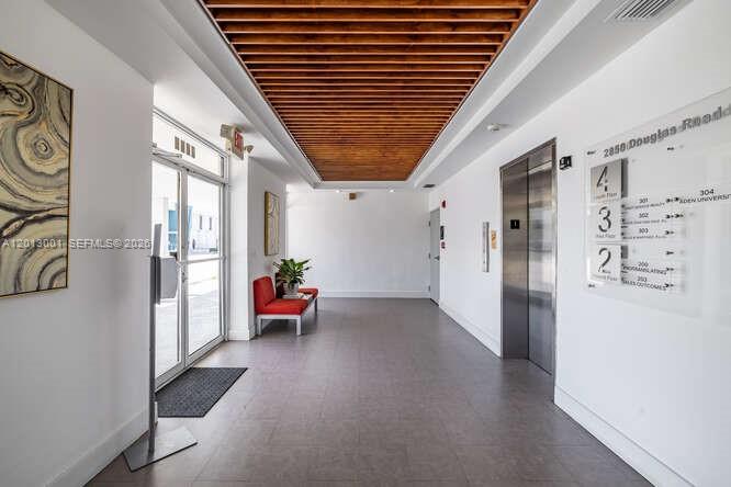 A modern building lobby features a slatted wood ceiling, gray tile floors, and an elevator — 2850 S Douglas Rd, Coral Gables FL 33134, CORAL GABLES, FL