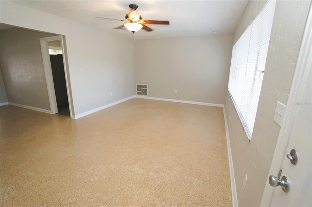 An empty room features tan carpet, beige walls, a ceiling fan, and a large window — 206 S WESTSHORE BOULEVARD, TAMPA, FL