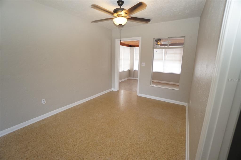 A room with beige walls, a ceiling fan, and speckled flooring leads to a sunroom — 206 S WESTSHORE BOULEVARD, TAMPA, FL
