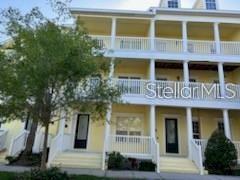 A three-story yellow townhouse features white railings, balconies, and front entry stairs — 203 MCLEODS WAY, WINTER SPRINGS, FL