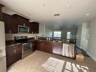 A kitchen features dark wood cabinets, stainless steel appliances, and tile flooring — 203 MCLEODS WAY, WINTER SPRINGS, FL