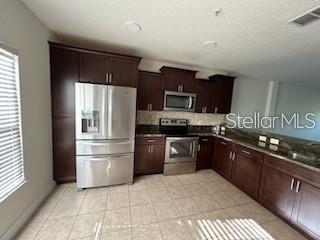 A kitchen features dark wood cabinets, stainless steel appliances, and tile flooring — 203 MCLEODS WAY, WINTER SPRINGS, FL