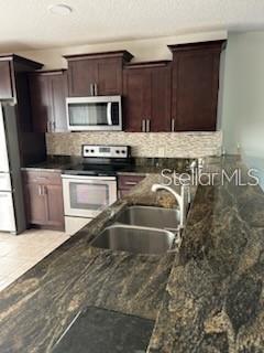 A kitchen features dark wood cabinets, stainless steel appliances, and a granite countertop with a sink — 203 MCLEODS WAY, WINTER SPRINGS, FL