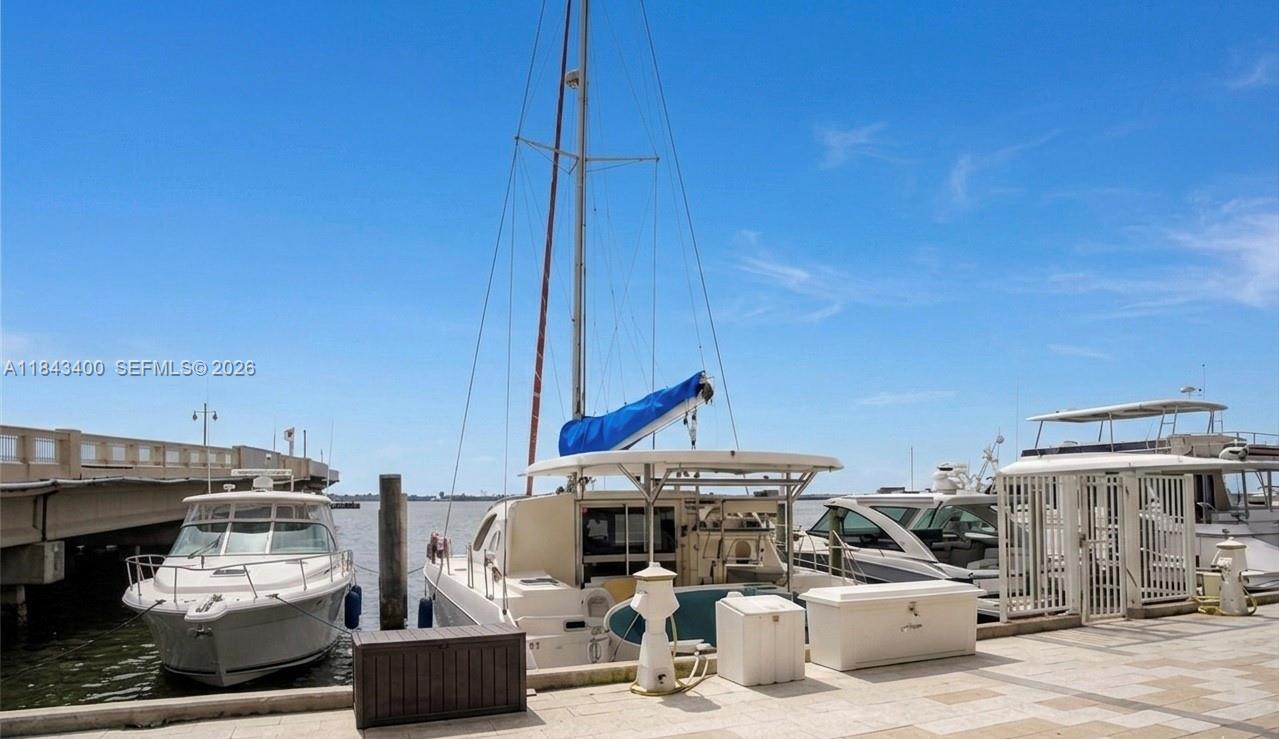 A sailboat and motorboats are docked at a marina next to a concrete bridge — 801 Brickell Bay Dr, Miami FL 33131, MIAMI, FL
