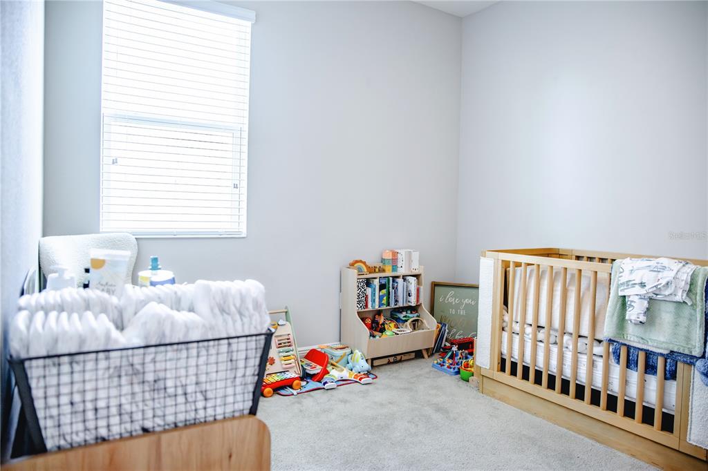 A nursery features a wooden crib, a toy bookshelf, and a wire basket of linens — 10452 LAGUNA PLAINS DRIVE, RIVERVIEW, FL