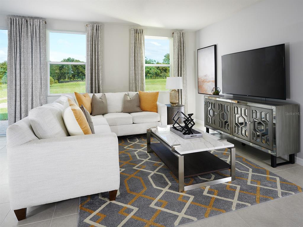 A living room features a white sectional sofa, a geometric rug, and a mirrored media console — 4585 RANGELAND WAY, ST CLOUD, FL