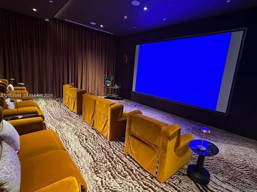 A home theater features rows of gold velvet armchairs, a large screen, and patterned carpeting — 77 SE 5th Street # 1014, Miami FL 33131, MIAMI, FL