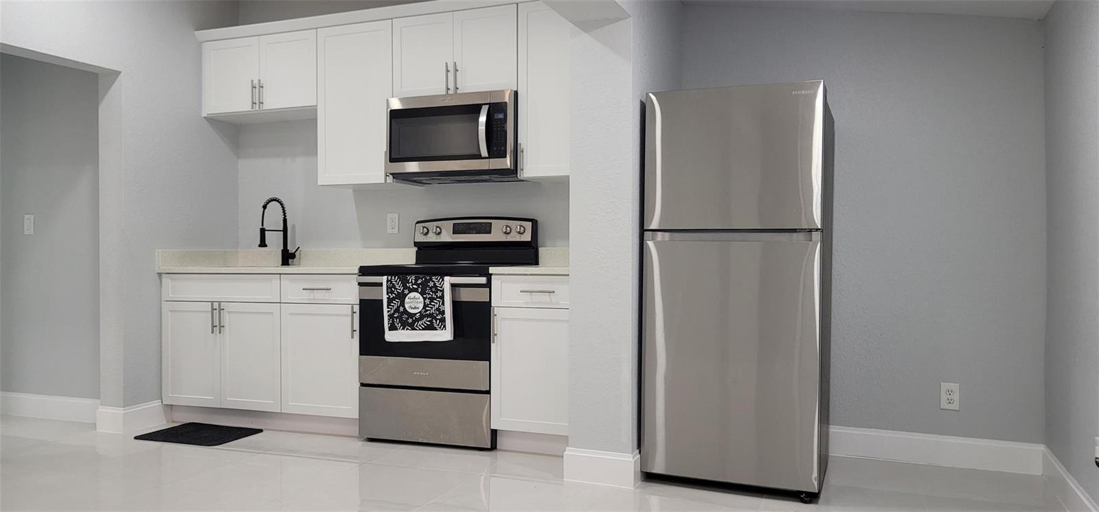 A kitchen features white cabinets, stainless steel appliances, and light gray walls — 4365 27th Avenue, Vero Beach FL 32967, VERO BEACH, FL