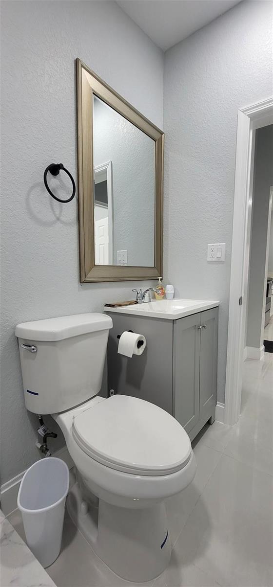 A small bathroom features a gray vanity, a white toilet, and a framed wall mirror — 4365 27th Avenue, Vero Beach FL 32967, VERO BEACH, FL