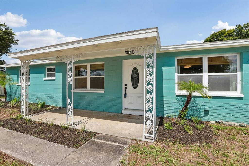 A turquoise, single-story house with a white front door and decorative metal porch supports — 8090 68TH STREET N, PINELLAS PARK, FL
