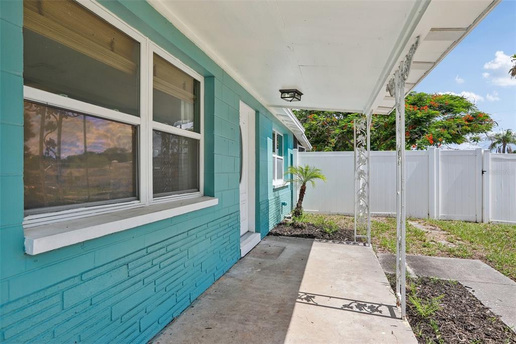 A teal painted brick house features a concrete front porch with decorative white metal supports — 8090 68TH STREET N, PINELLAS PARK, FL