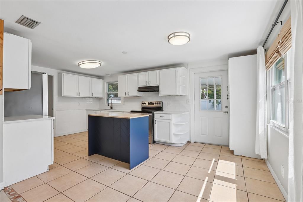 A kitchen featuring white cabinets, a blue island, tile flooring, and a glass-paneled exterior door — 8090 68TH STREET N, PINELLAS PARK, FL