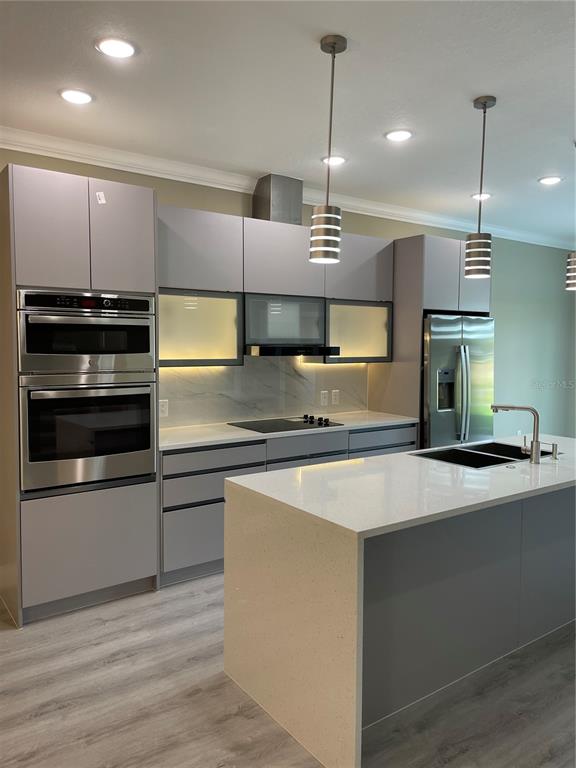 A modern kitchen features gray cabinetry, stainless steel appliances, a quartz island, and pendant lighting — 1810 BRENTWOOD COURT, DAVENPORT, FL