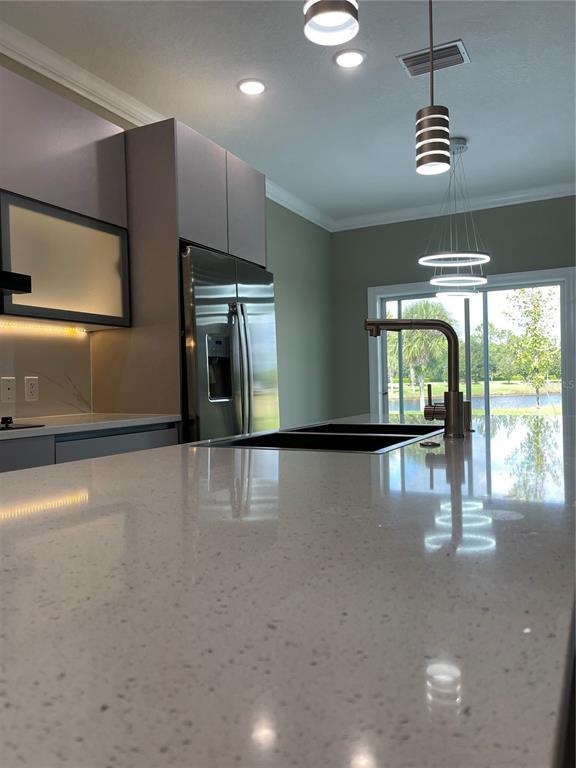 A modern kitchen features a large quartz island, stainless steel appliances, and pendant lighting — 1810 BRENTWOOD COURT, DAVENPORT, FL
