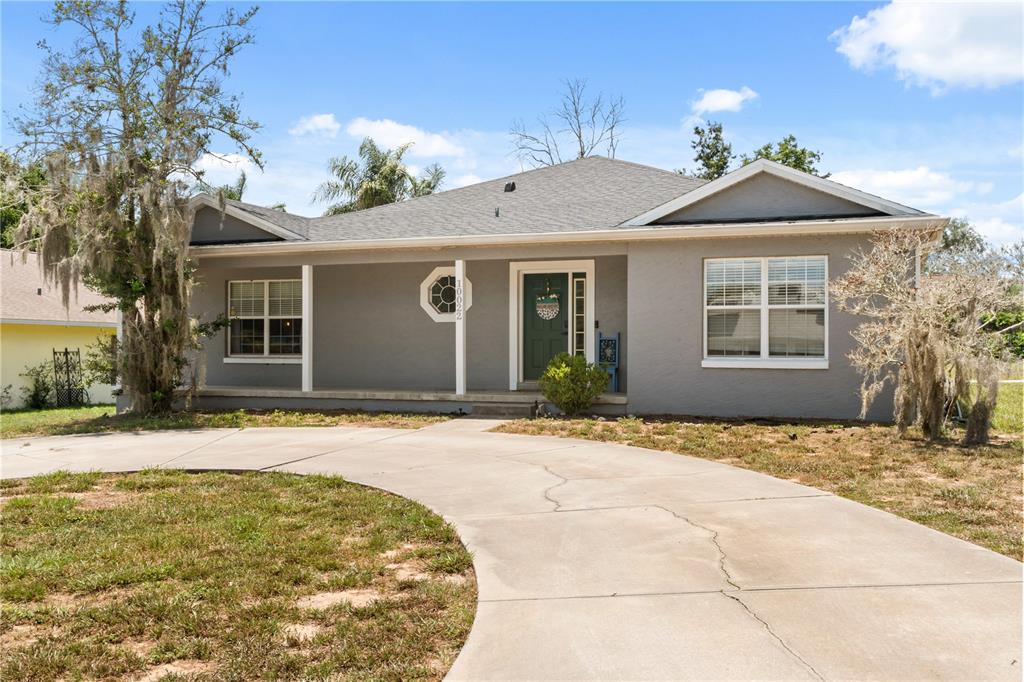 A single-story gray house with a covered porch and a curved concrete driveway — 10022 CAROLE PLACE, LEESBURG, FL