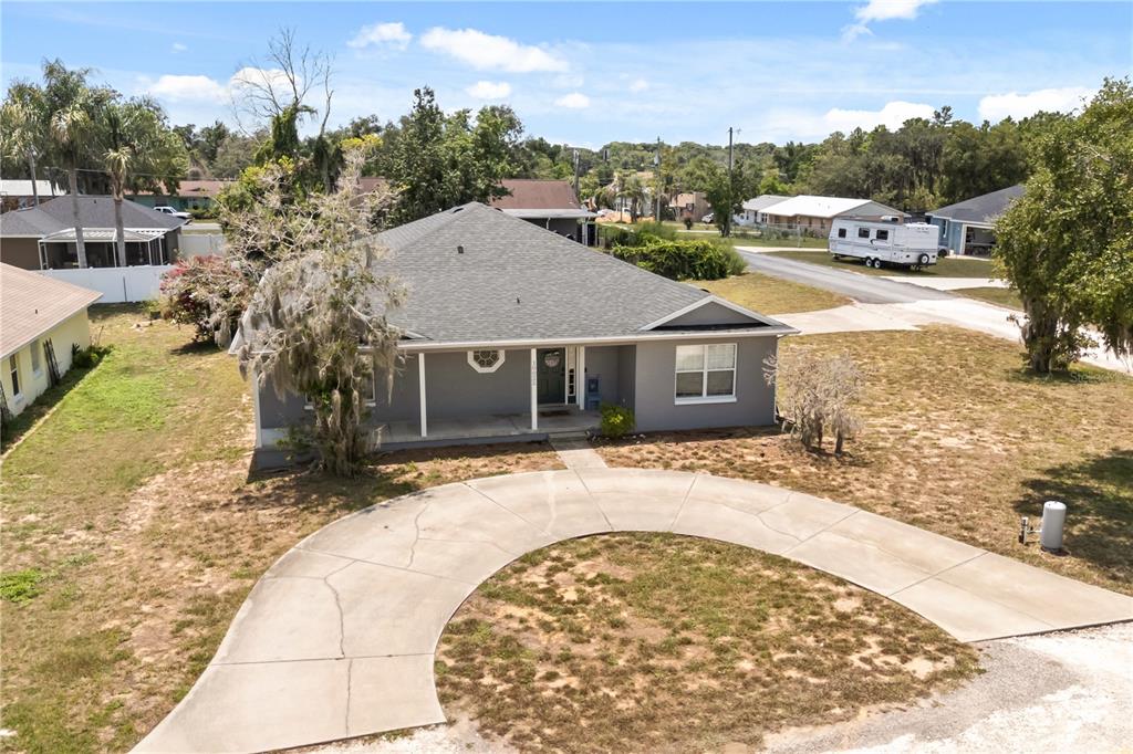 An aerial view of a gray single-story house with a circular concrete driveway — 10022 CAROLE PLACE, LEESBURG, FL