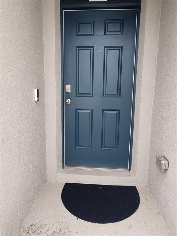 A blue front door with a keypad lock and a doorbell camera sits in a recessed entryway — 1051 GRIFFON AVENUE, LAKE ALFRED, FL