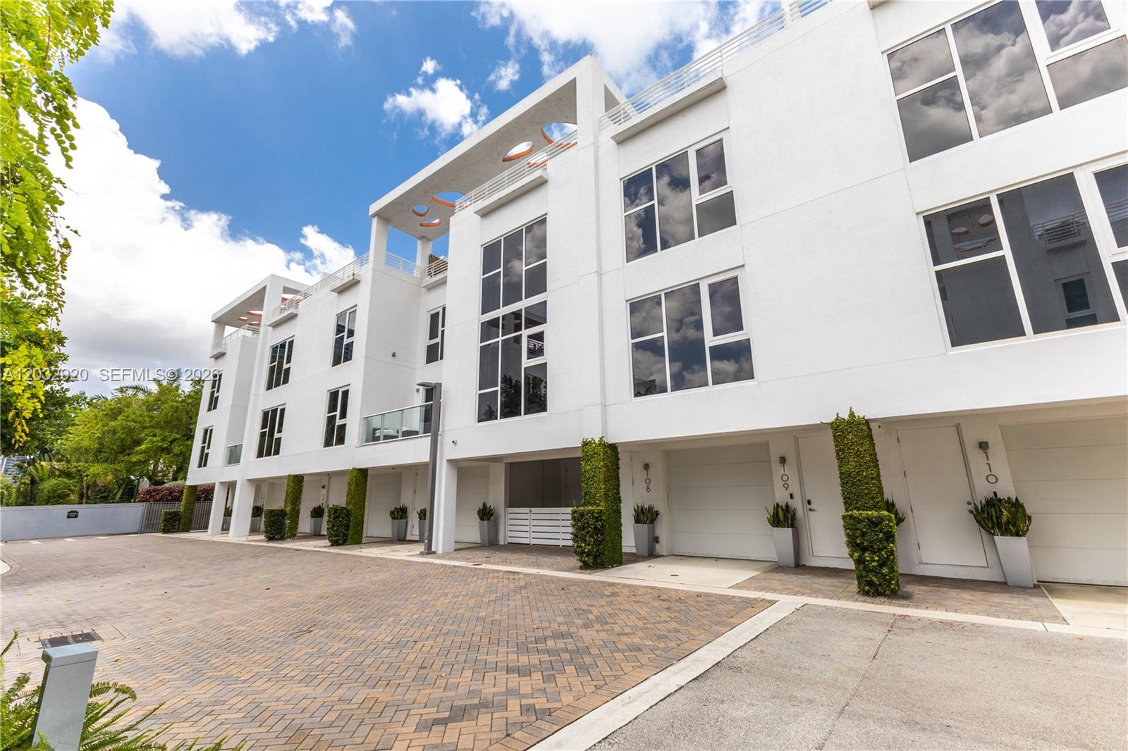 A modern white multi-story townhouse complex features a paved driveway and vertical landscaping accents — 455 NE 39th St # 109, Miami FL 33137, MIAMI, FL