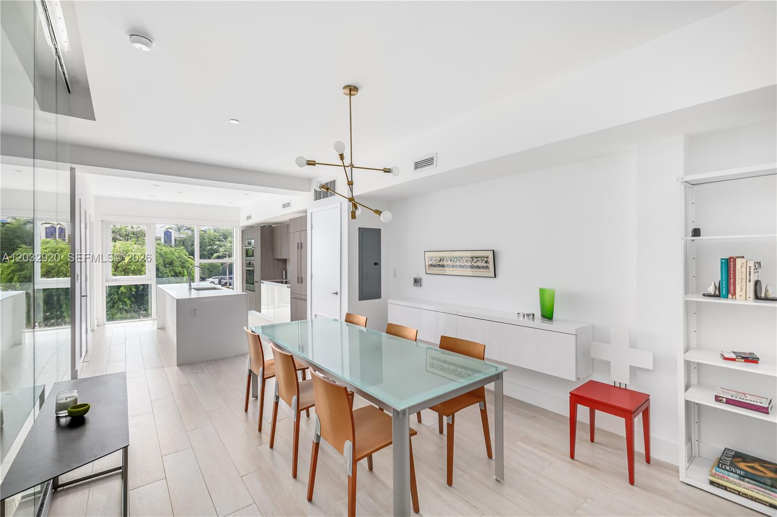 A modern dining room features a glass-topped table, wooden chairs, and an adjacent kitchen — 455 NE 39th St # 109, Miami FL 33137, MIAMI, FL