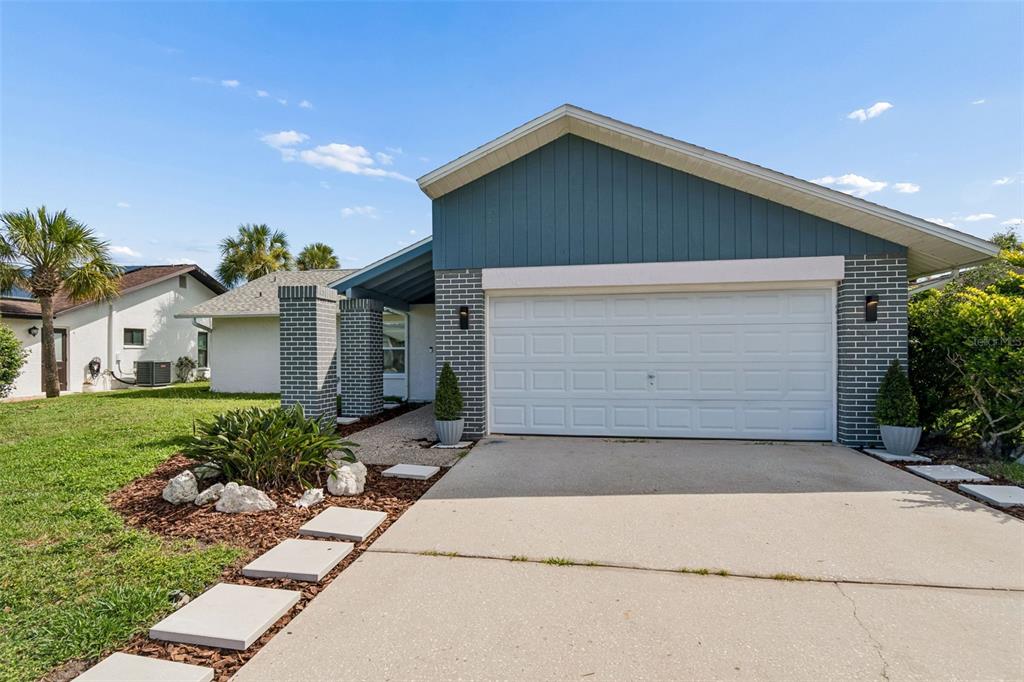 A single-story house with a blue-painted gable, brick accents, and a concrete driveway — 4559 INGERSOL PLACE, NEW PORT RICHEY, FL