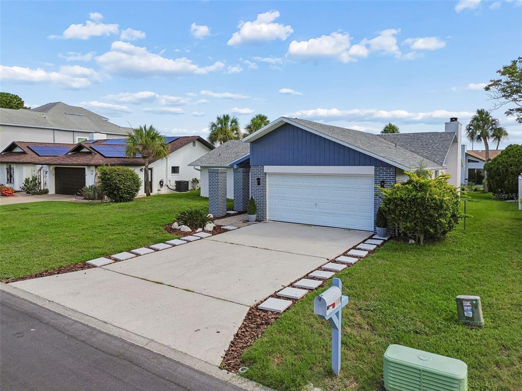 A single-story house with a blue facade, white garage door, and a concrete driveway — 4559 INGERSOL PLACE, NEW PORT RICHEY, FL