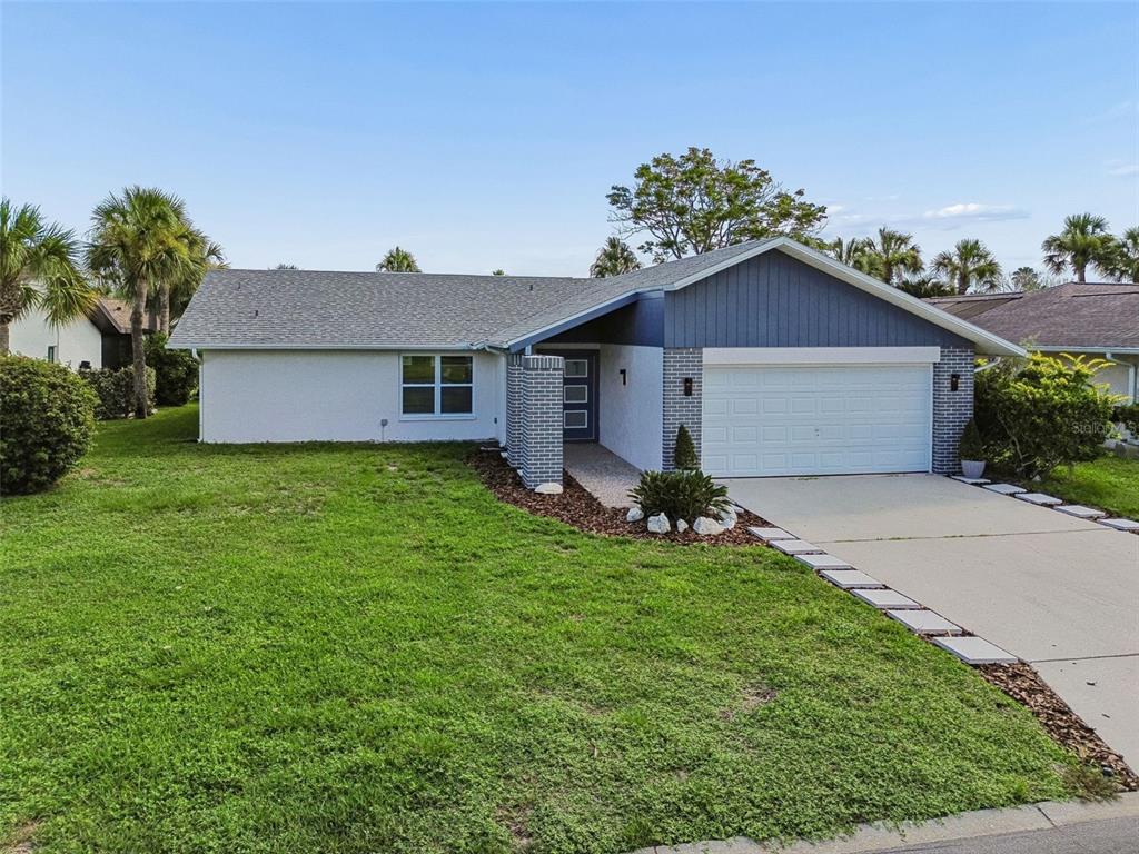 A single-story house with a white exterior, blue siding, and a two-car garage — 4559 INGERSOL PLACE, NEW PORT RICHEY, FL