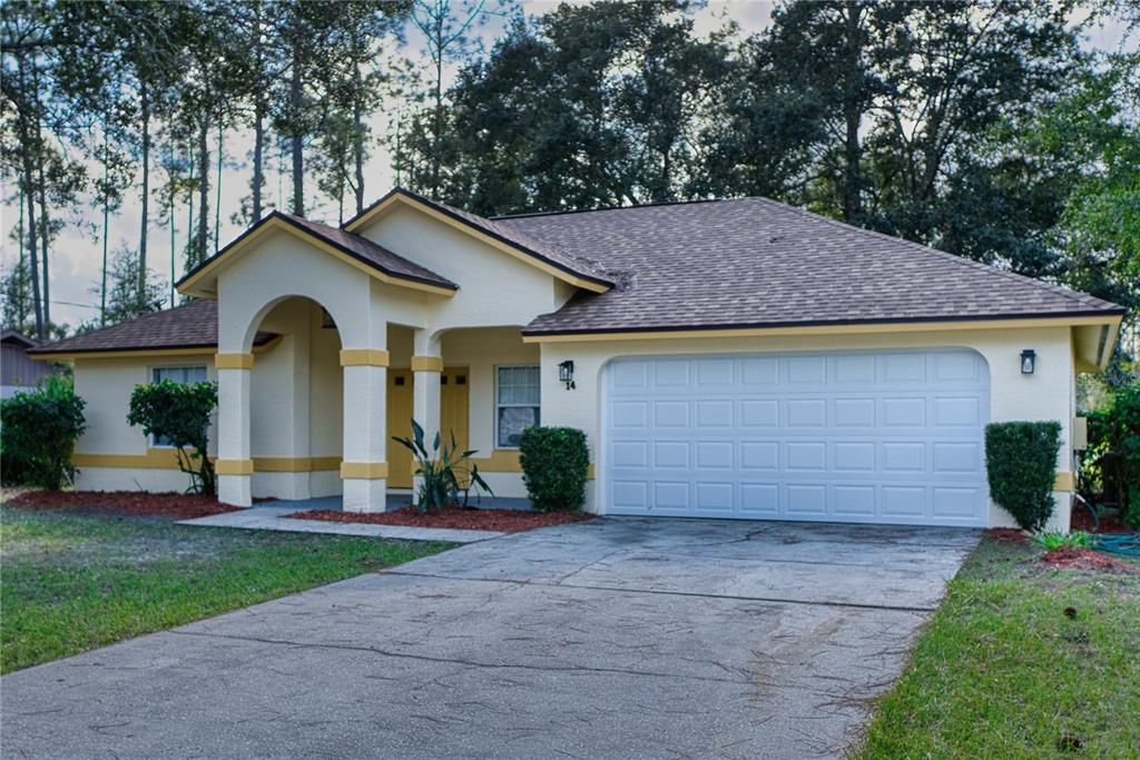 A single-story house with a white stucco exterior, yellow trim, and a two-car garage — 14 WELLSHIRE LANE, PALM COAST, FL
