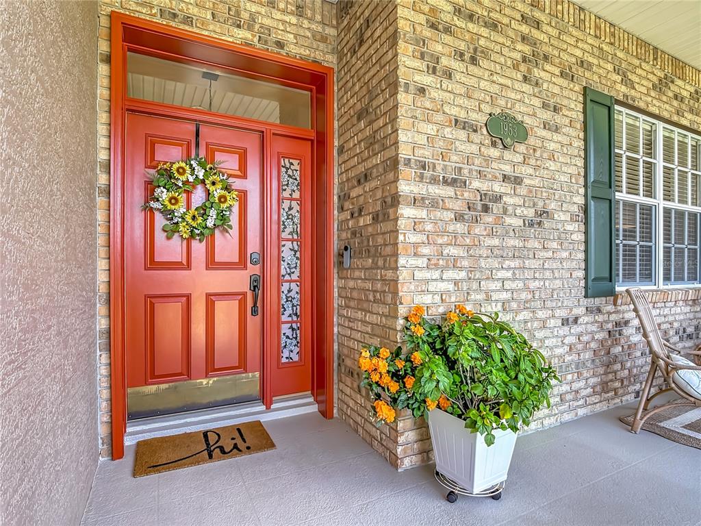 A bright orange front door with a sunflower wreath sits beside a brick exterior wall — 1953 VIEWPOINT LANDINGS ROAD, LAKELAND, FL