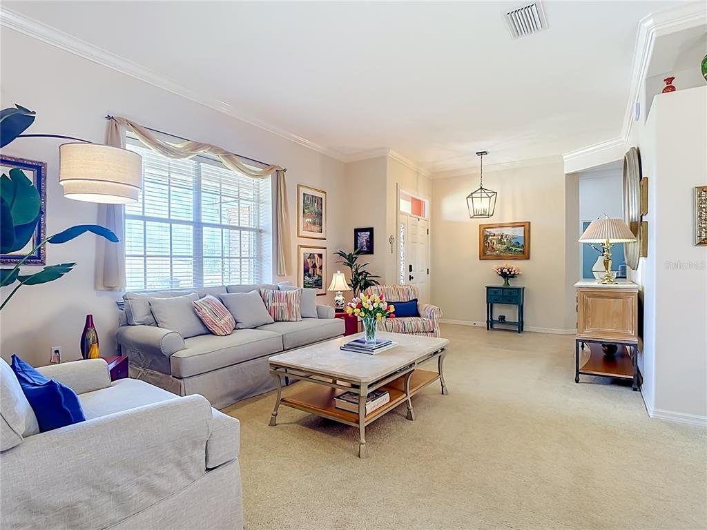 A living room features a light gray sofa, a coffee table, and beige carpeting — 1953 VIEWPOINT LANDINGS ROAD, LAKELAND, FL