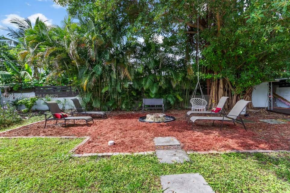 A backyard features a fire pit, lounge chairs, and a hanging chair on mulch — 402 NW 102nd St, Miami FL 33150, MIAMI, FL