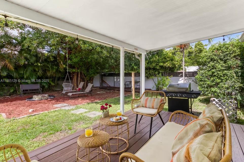 A covered wooden deck overlooks a backyard with a fire pit and lounge seating — 402 NW 102nd St, Miami FL 33150, MIAMI, FL