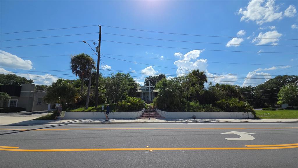 A house with a large white cross in the front yard sits behind a retaining wall — 236 N AMELIA AVENUE, DELAND, FL