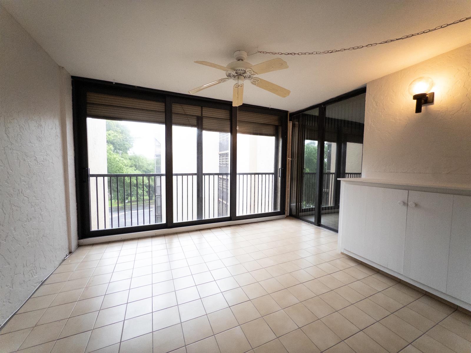 An empty, rectangular room features light-colored wood-look flooring, white walls, and a ceiling fan — 2800 N 46th # A502, Hollywood FL 33021, HOLLYWOOD, FL