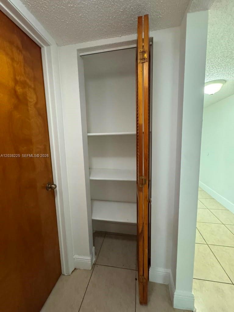 A narrow closet with white shelves and a partially open wooden bifold door — HIALEAH, FL