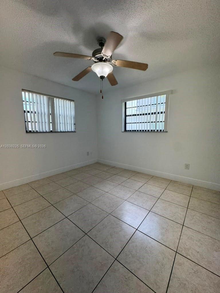 An empty room features white walls, light-colored tile flooring, and a ceiling fan — HIALEAH, FL