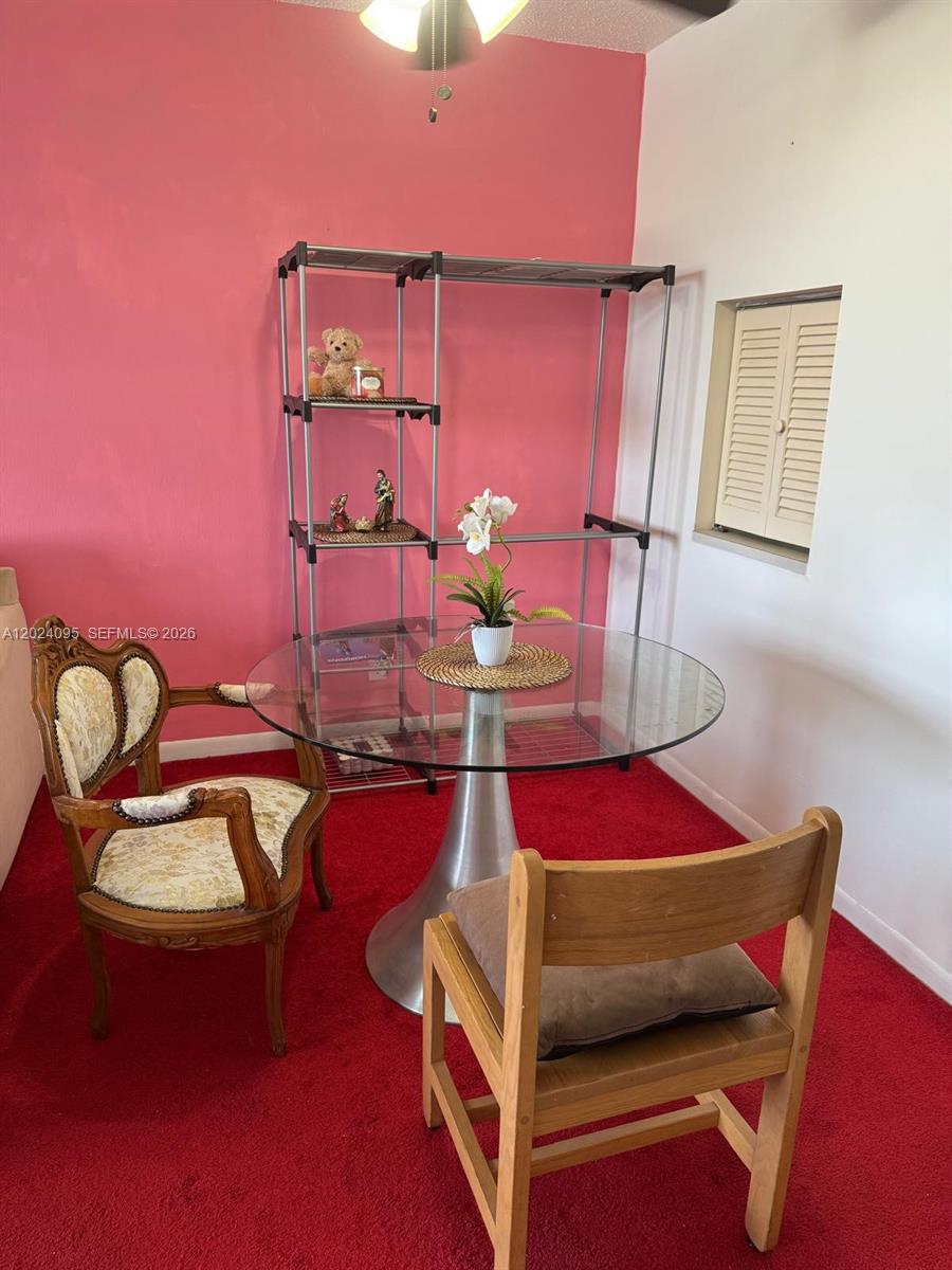 A dining area features a glass table, two chairs, and a metal shelving unit — HOLLYWOOD, FL