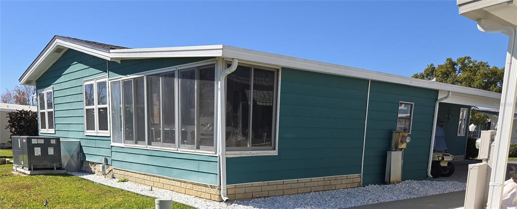A teal mobile home with a screened-in porch, white trim, and a gravel landscape — 312 TOWNBRIDGE DRIVE, HAINES CITY, FL