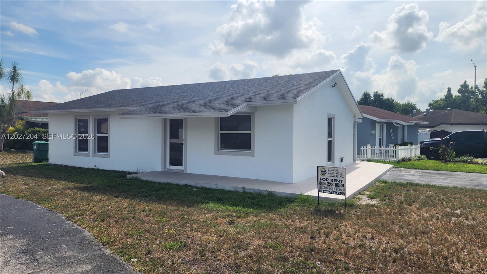 A white, single-story house with a gray shingled roof sits on a grassy lot — 13741 SW 46th Ter, Miami FL 33175, MIAMI, FL