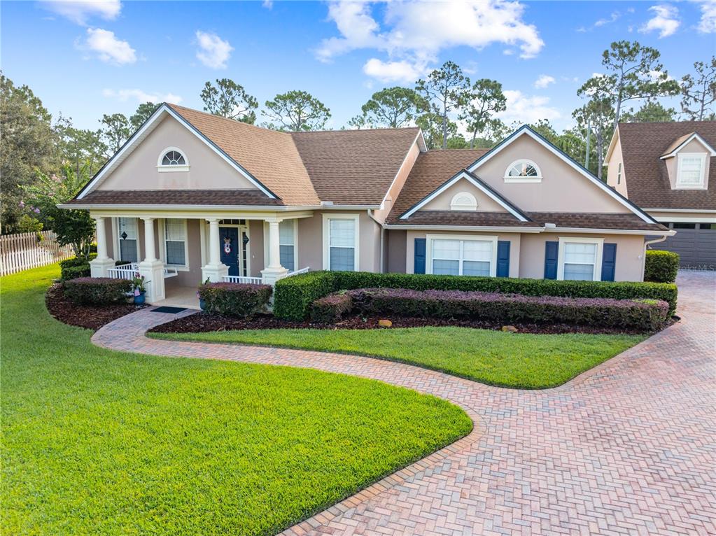 A single-story house with a brick walkway, manicured hedges, and a multi-gabled roof — 1803 CHARLES COURT, ST CLOUD, FL