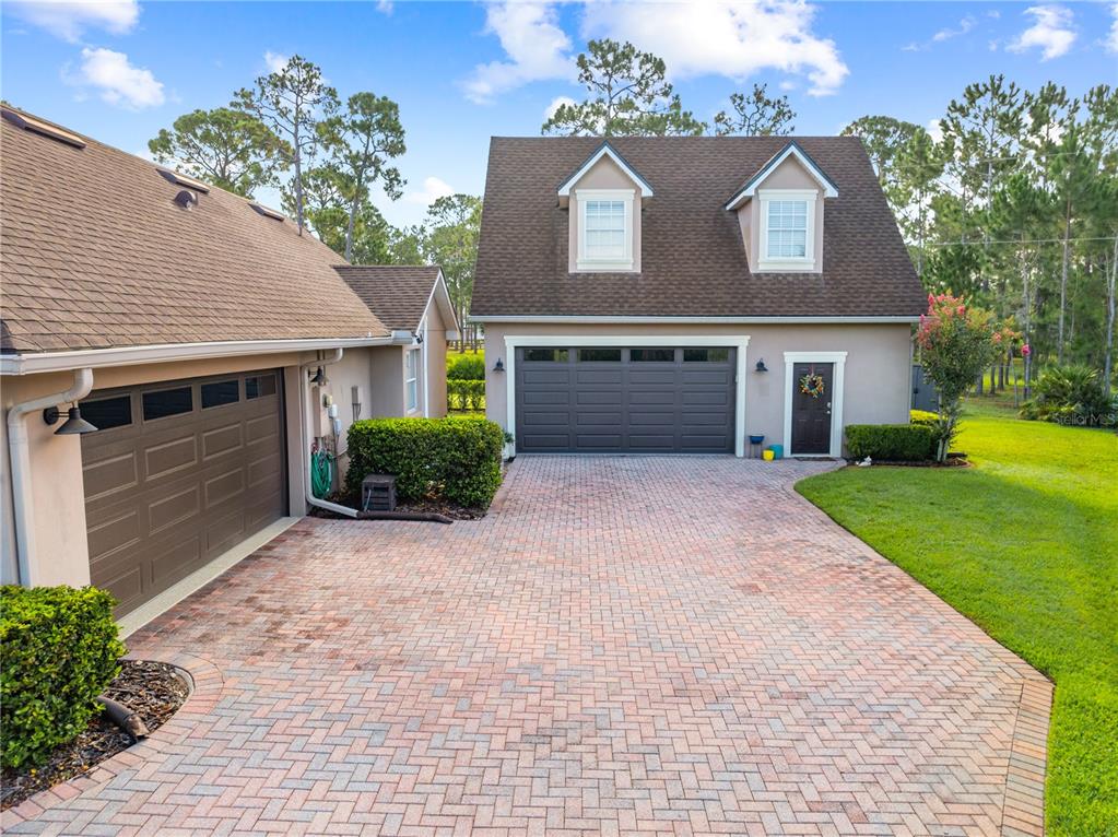 A detached garage with a second-story loft sits behind a brick-paved driveway — 1803 CHARLES COURT, ST CLOUD, FL