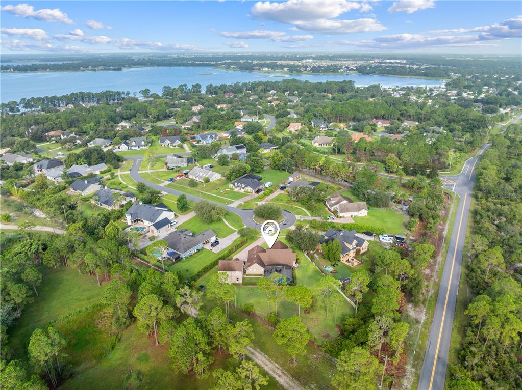 An aerial view shows a suburban house with a pool surrounded by trees and roads — 1803 CHARLES COURT, ST CLOUD, FL